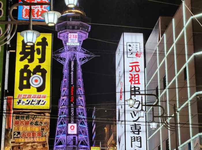Tsutenkaku Tower surrounded by traditional shops and neon signs. Photo by Da-shika on Unsplash