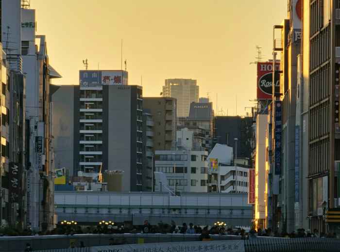 Guests walking with host near Dotombori riverbank at sunset Photo by Muhammad Luqman Haqiem Bin Nazri on Unsplash