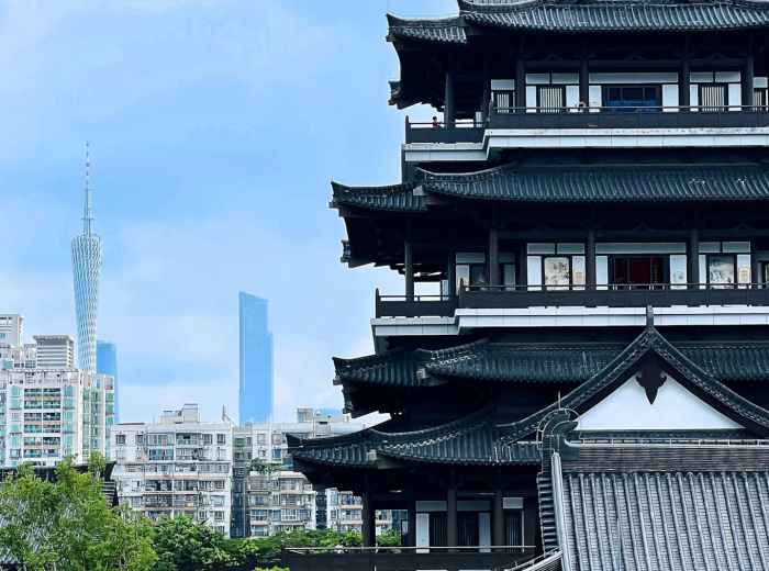 Traditional temple gate with modern city skyline visible in background. Photo by Kakohri H on Unsplash
