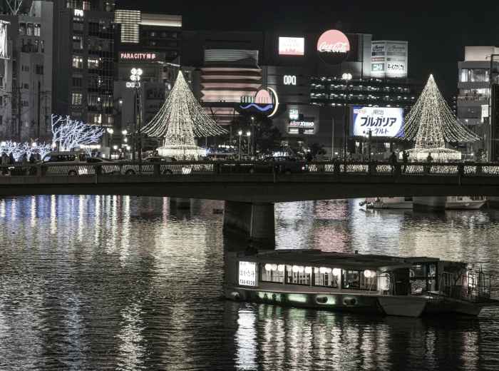 The main winter illuminations at Osaka Hikari Renaissance reflected in the river, with couples and families viewing the display Photo by Nichika Sakurai on Unsplash