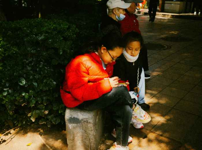 A family consulting schedules while children wait patiently with backpacks Photo by Frank Ching on Unsplash