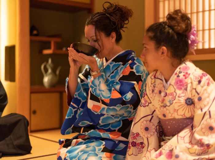 Traditional tea ceremony in progress with precise hand movements and seasonal arrangements