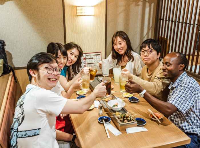 Intimate izakaya scene with host introducing dishes
