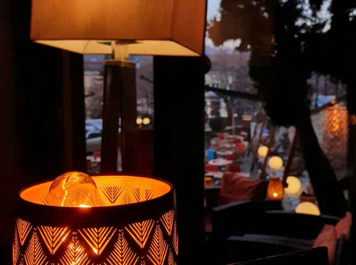 Traditional riverside restaurant with paper lanterns reflected in water at dusk Photo by Stefania Banut on Unsplash