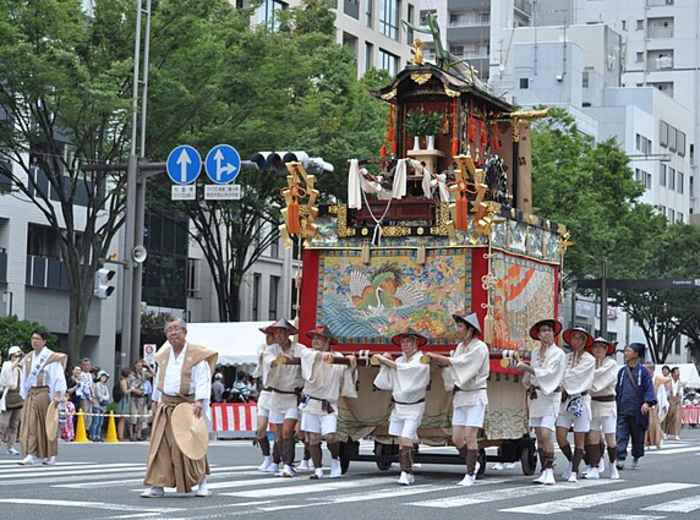 Tall decorated wooden floats pass through busy streets during a lively traditional festival