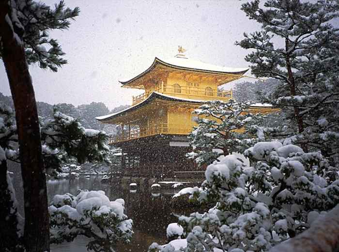 Snow blanketing gardens and pond around a gold-covered pavilion creating a serene winter scene