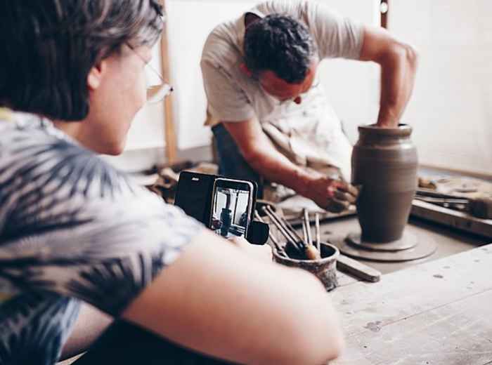 Artisan shaping clay on a spinning wheel while guiding participants in a traditional ceramics studio