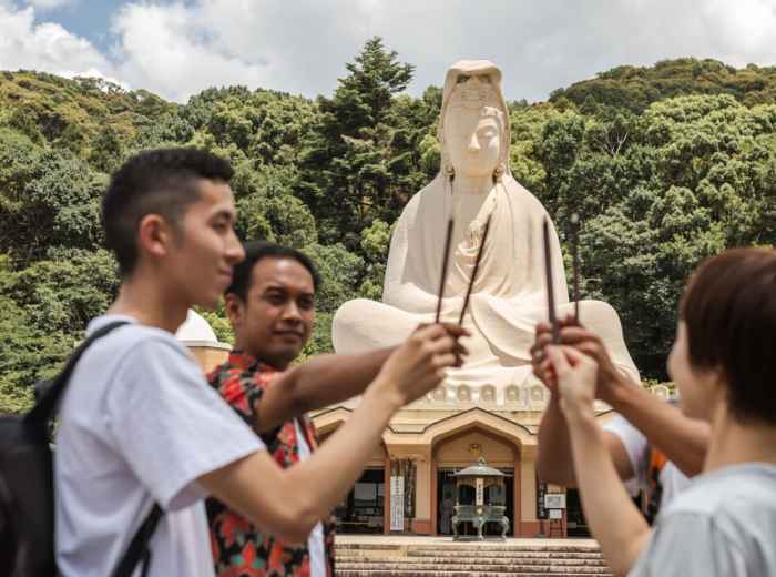 People bow in front of an altar with incense smoke rising and offerings displayed