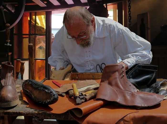 Leather craftsman at work in Florence, traditional tools and shoes on the bench
