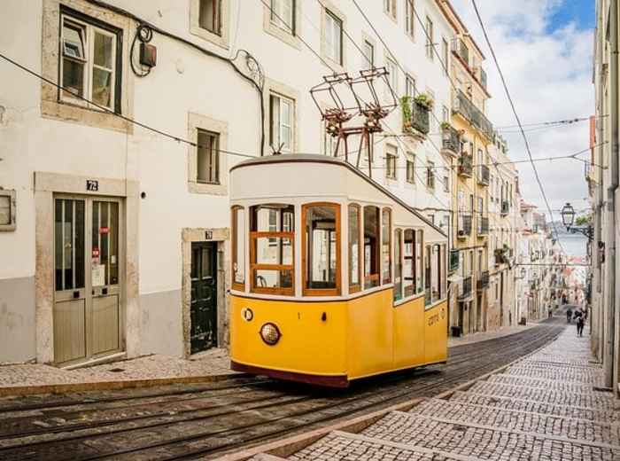 Lisbon’s yellow Tram 28 climbing a narrow hill street in the historic center