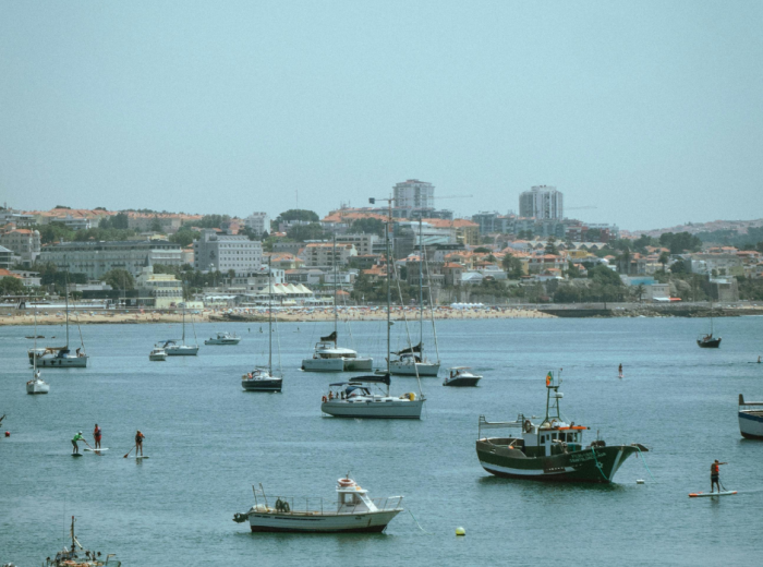 Seafront of Cascais with fishing boats, beach, and promenade under clear skies