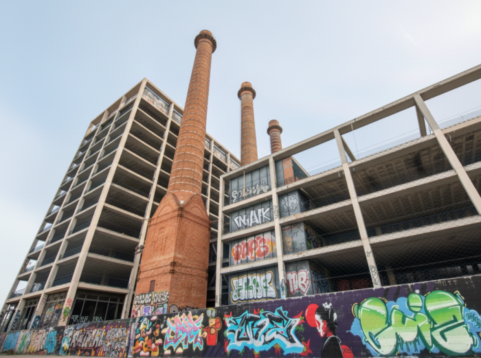 Three tall brick smokestacks rising above colorful graffiti walls