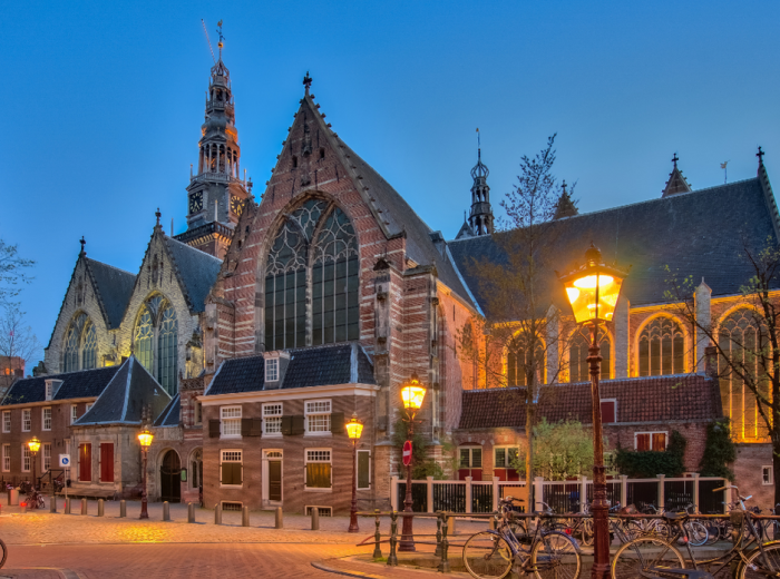 Oude Kerk lit at night with gentle light under a blue sky