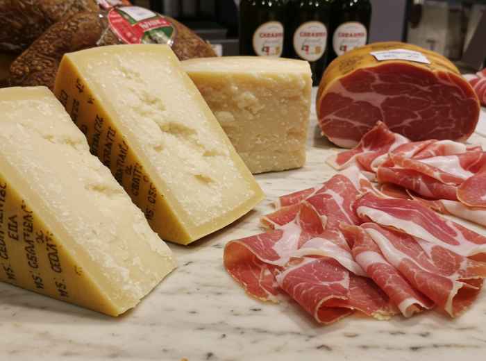 Parmigiano wedges and hand-sliced prosciutto at a small alimentari