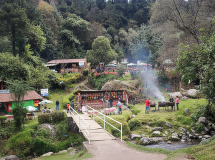 Families grilling food by the river in Los Dinamos 