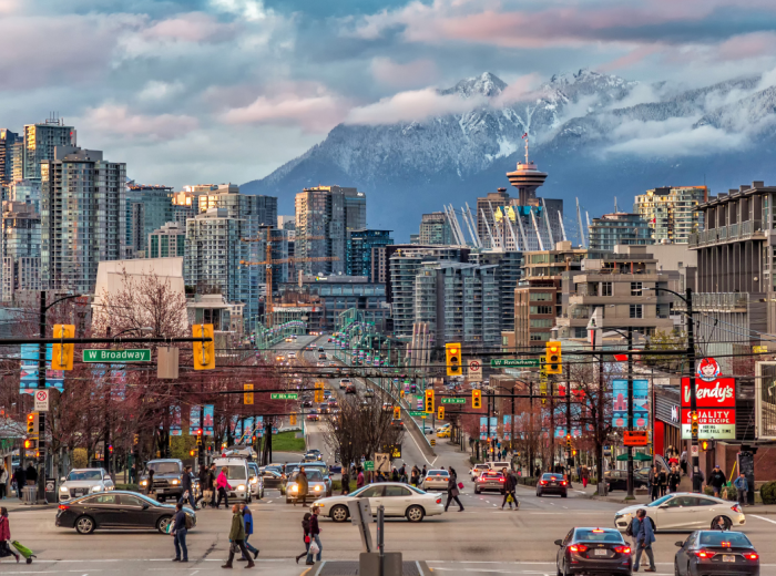 Street view of a busy Vancouver street with mountains in the distance