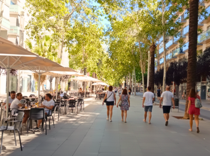 Rambla del Poblenou in the morening with locals walking and sitting at a coffee shop