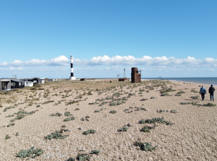 Shingle beach with fishing huts and a lighthouse at Dungeness