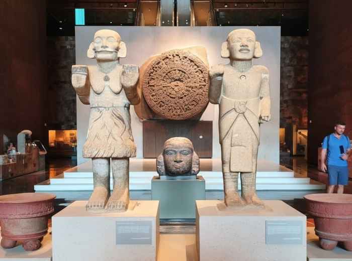 Visitor before massive stone carving in museum hall