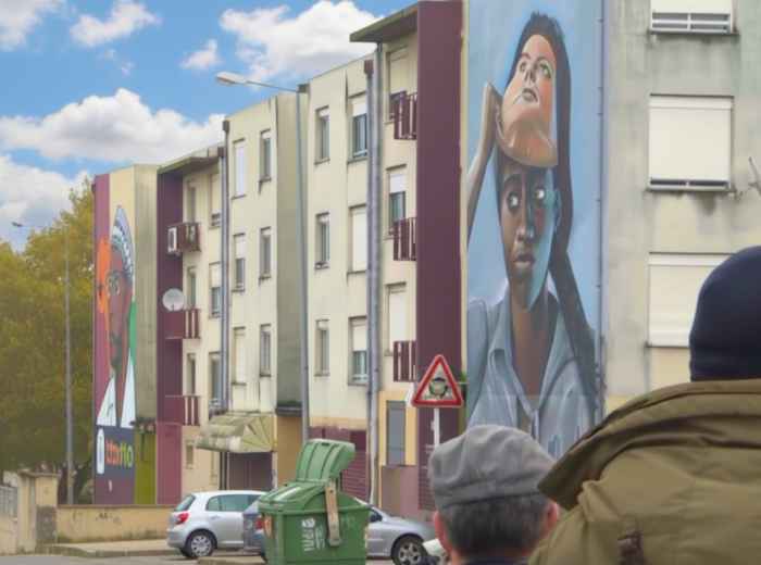 Colorful murals covering buildings in Quinta do Mocho, showcasing street art