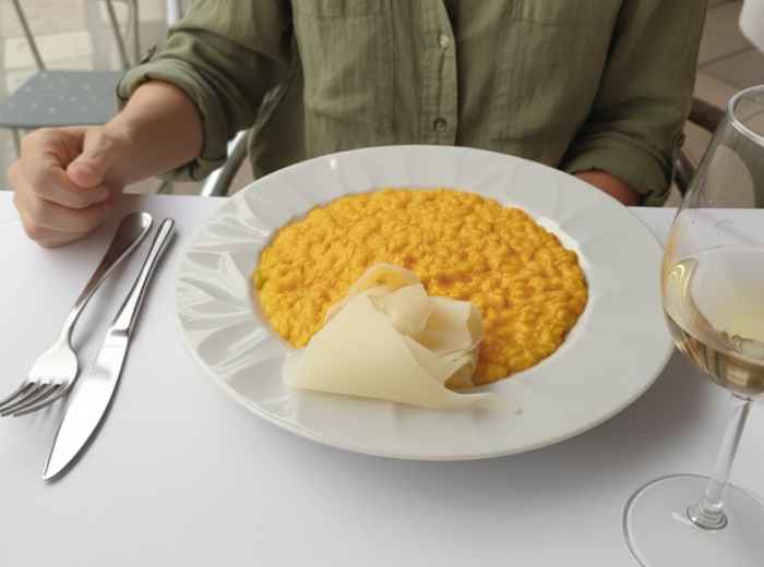 Golden saffron risotto served in traditional Milanese trattoria setting