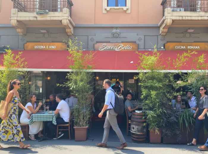 Busy street in Porta Romana with people dining at a neighborhood trattoria