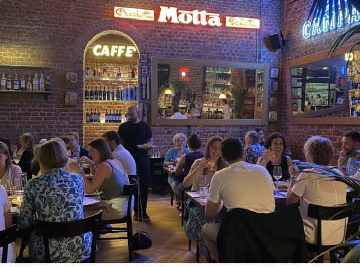 Traditional Milanese trattoria interior with locals dining at wooden tables
