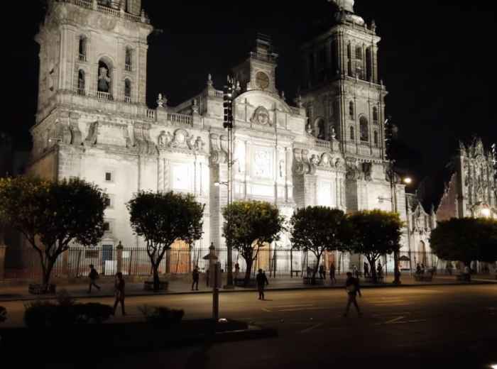 Cathedral and Zócalo illuminated at night with few people