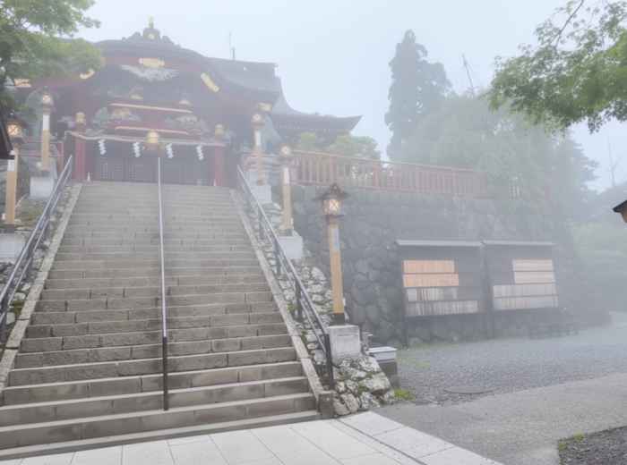Musashi Mitake Shrine emerging from morning mist with cedar trees around