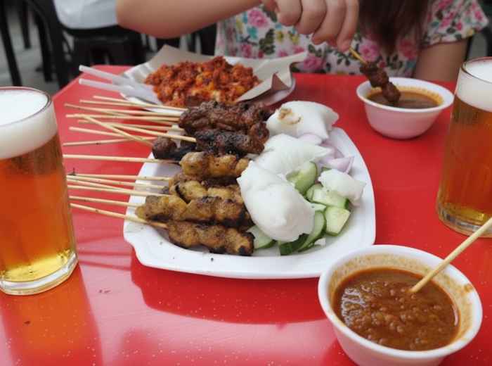 Charcoal-grilled satay skewers with thick peanut sauce, cucumber, rice cakes