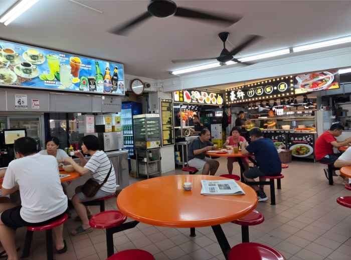 Traditional kopitiam with locals at tables under warm lighting and ceiling fans