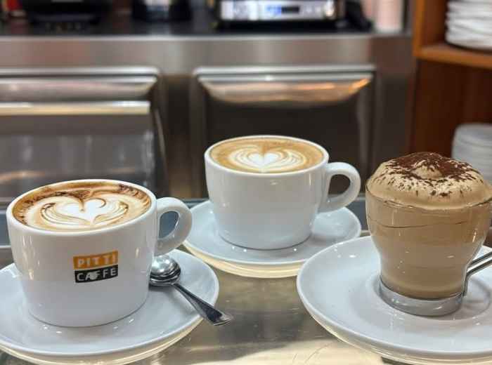 Locals standing at espresso bar counter with barista pulling shots in morning light