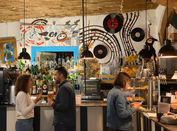 Locals laughing over shared meal at marble counter with house wine and empty plates