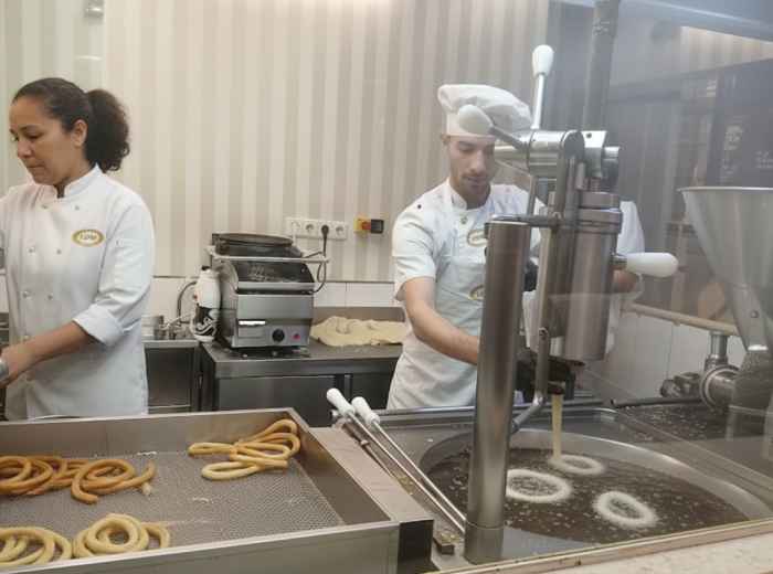 churros being piped into hot oil at a churrería