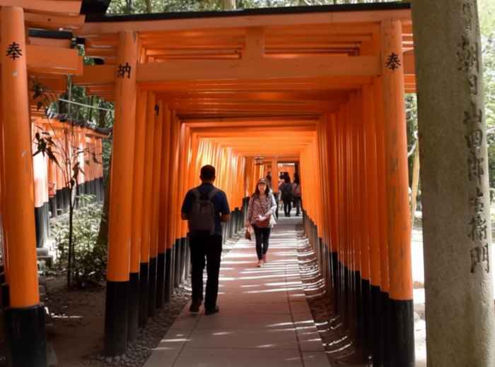 Visitors walking through vermilion torii gates at Fushimi Inari Shrine, Kyoto