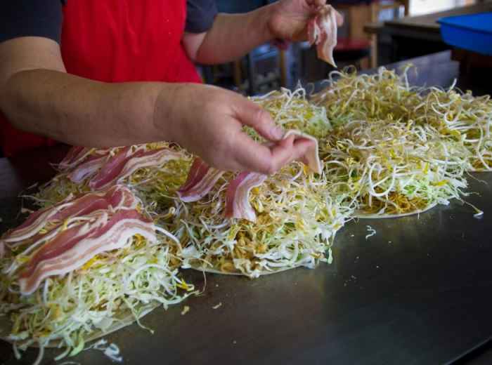 Hiroshima-style okonomiyaki cooking on a teppan grill