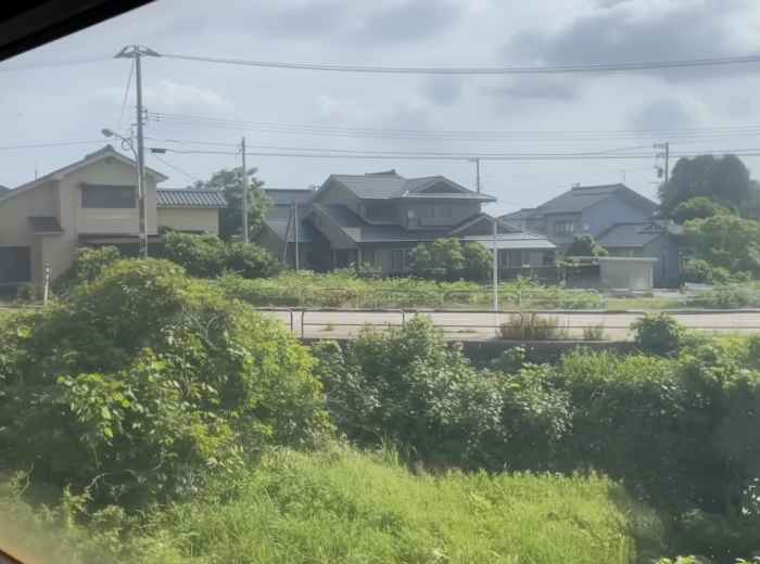 View from a train window showing suburban houses and greenery in Japan