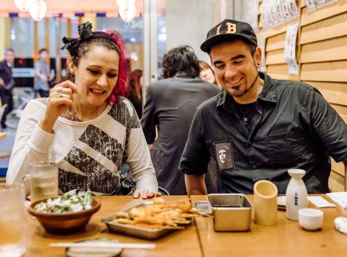 Travelers enjoying skewered food and drinks at a casual Japanese restaurant in Osaka