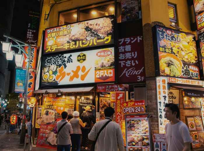 Busy street and 24 hour restaurant for ramen with bright signs, Tokyo