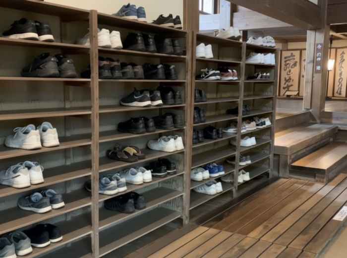 Shoes neatly lined on shelves at the entrance of a traditional Japanese building, showing proper indoor etiquette