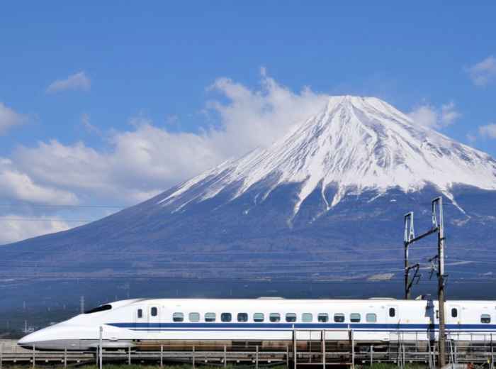 Shinkansen bullet train passing Mount Fuji with cherry blossoms