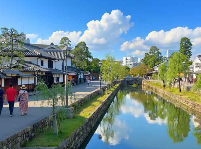 Quiet canal lined with white storehouses and willow trees in Kurashiki