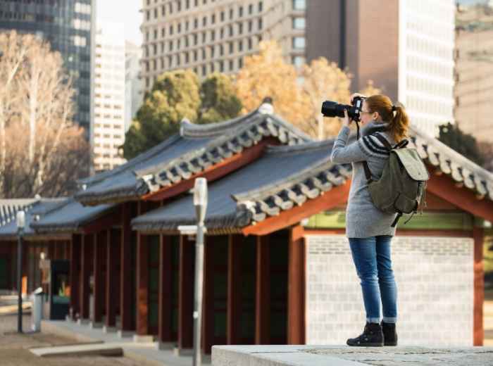 Soft afternoon light on palace rooftops framed by the modern Seoul skyline