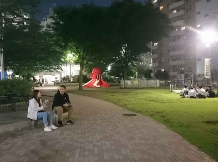 A quiet Japanese neighborhood park with people relaxing and talking