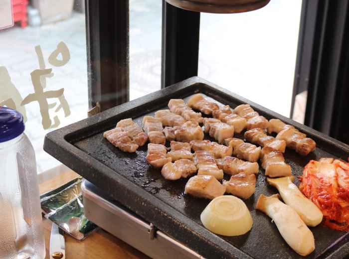 Pork grilling on tabletop BBQ in Seoul restaurant