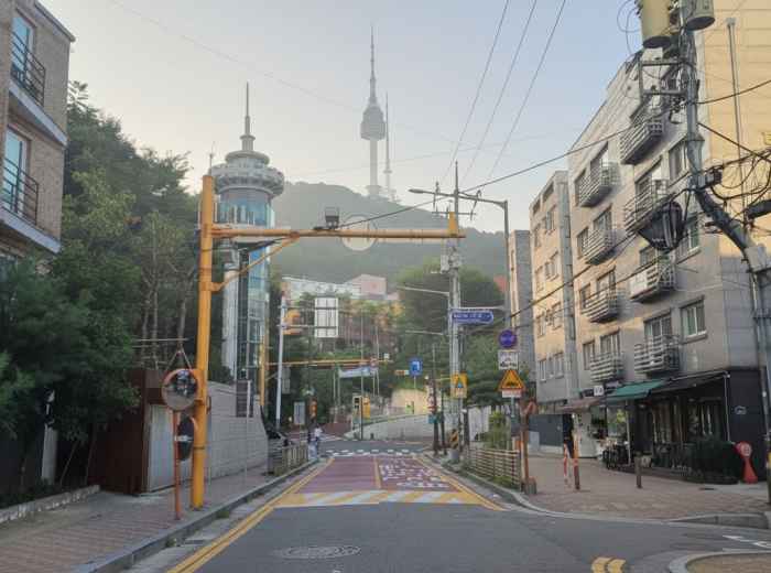 Quiet Seoul street at soft sunrise beneath Namsan Tower