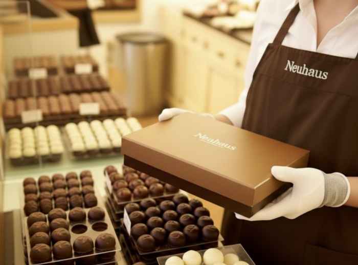 Neuhaus staff holding a boxed selection of Belgian pralines