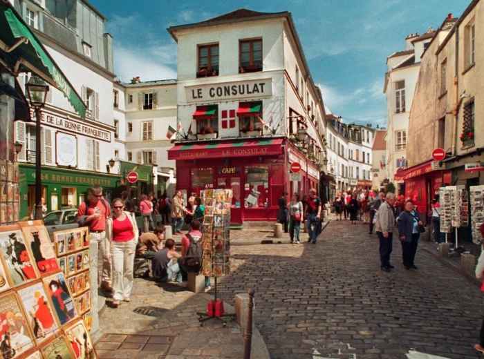 Montmartre street with Le Consulat and art stalls in soft afternoon light.