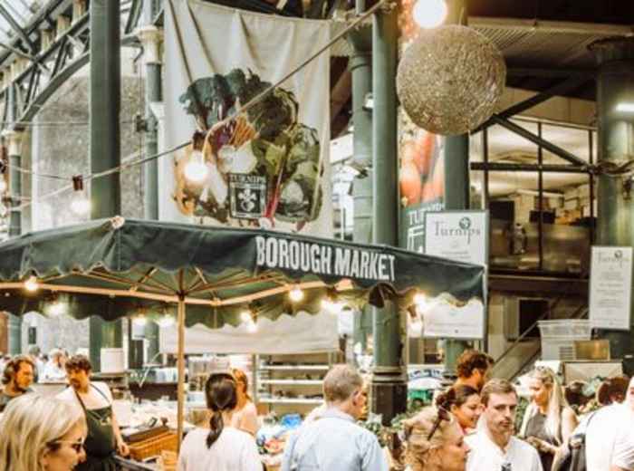 Visitors browsing food stalls beneath Borough Market’s historic canopy