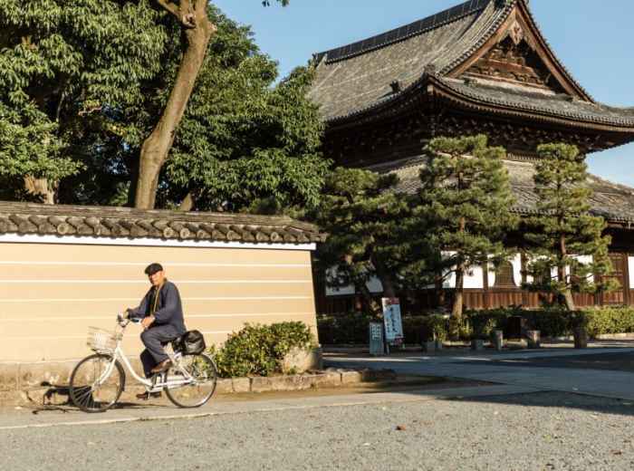 Cyclist passing a temple wall on a quiet Kyoto morning 